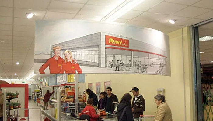 Pannello stampato curvo in sospensione all'interno di un supermercato Penny Market.