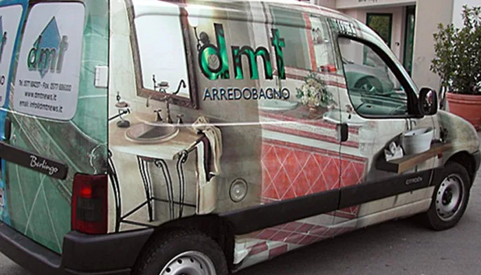 Furgone con grafica personalizzata per 'DMT Arredobagno' con immagini fotografiche di bagni arredati lungo tutta la carrozzeria