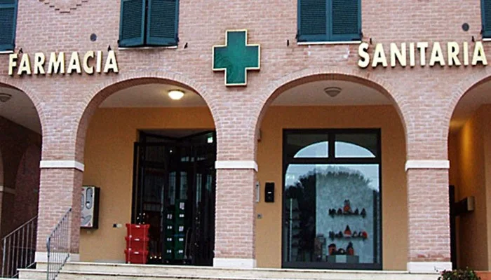 Insegna luminosa architettonica per farmacia. Croce verde al neon bordata in ottone e lettere singole in ottone.